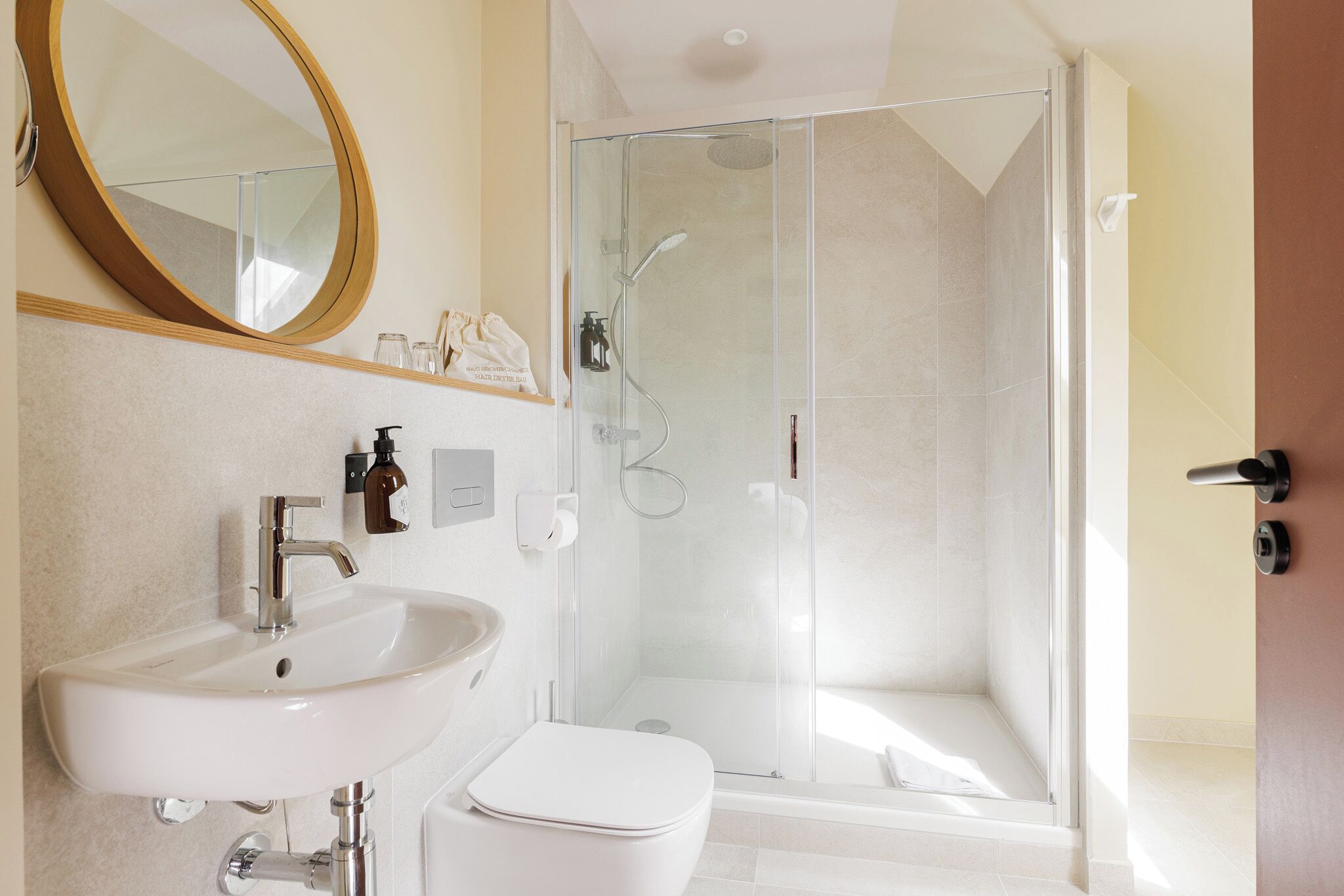 Un baño moderno con lavamanos blanco, inodoro y ducha con cerramiento de vidrio.