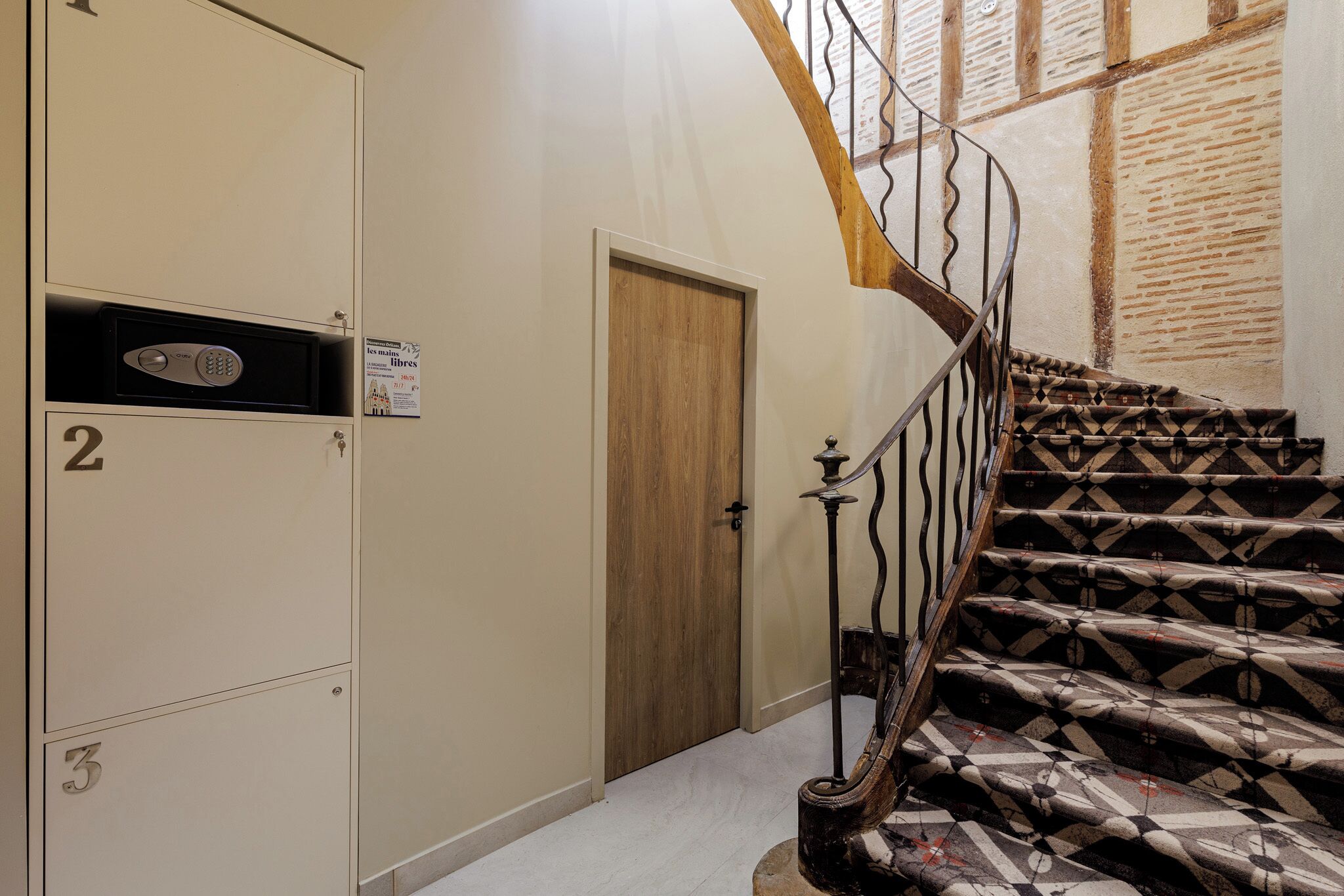 Una escalera con alfombra estampada, una puerta de madera y una barandilla de metal.