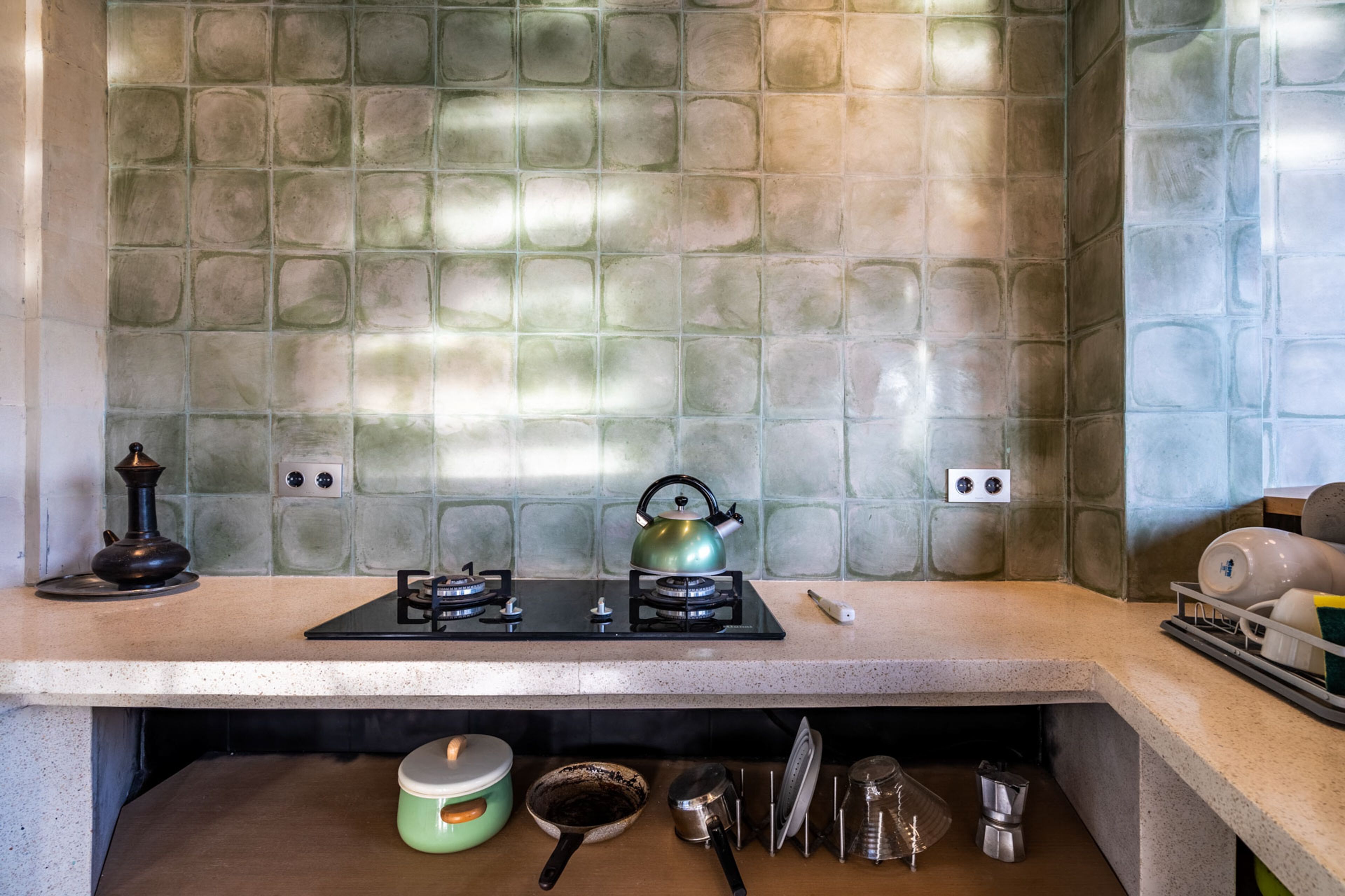 Una cucina con zoccolo in piastrelle, piano cottura a gas e diversi utensili da cucina.