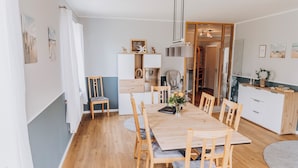 Una cocina moderna con armarios blancos, una mesa de comedor de madera y un horno empotrado.