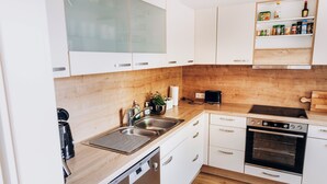 Una cocina moderna con armarios blancos, encimera de madera, horno empotrado y cafetera.