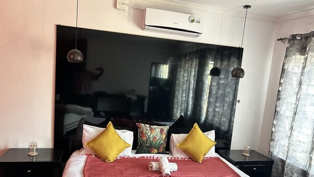 A hotel room with a large bed, a flat-screen TV, and a modern design. - The White House  (Phalaborwa)
