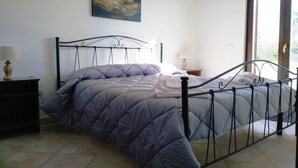 Una camera da letto con un letto, un comodino, una lampada, un quadro appeso al muro e una finestra.