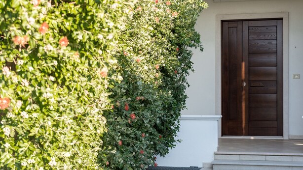 Una casa con una porta in legno scuro, decorazioni bianche e un ingresso con lastricato in pietra.