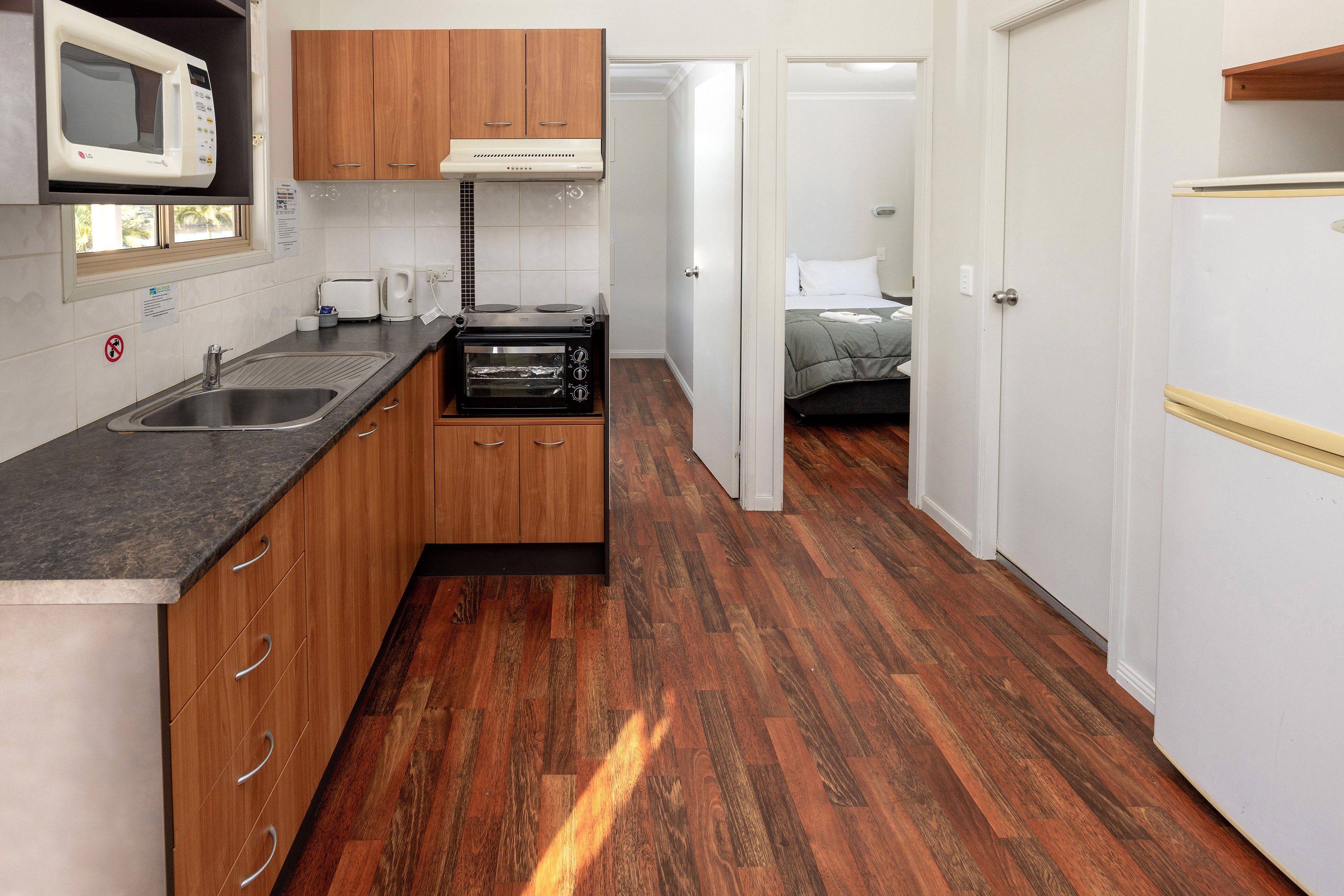 A compact kitchen with wooden cabinets, a built-in microwave, a toaster, and a stove.