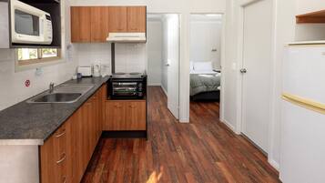 A compact kitchen with wooden cabinets, a built-in microwave, a toaster, and a stove.
