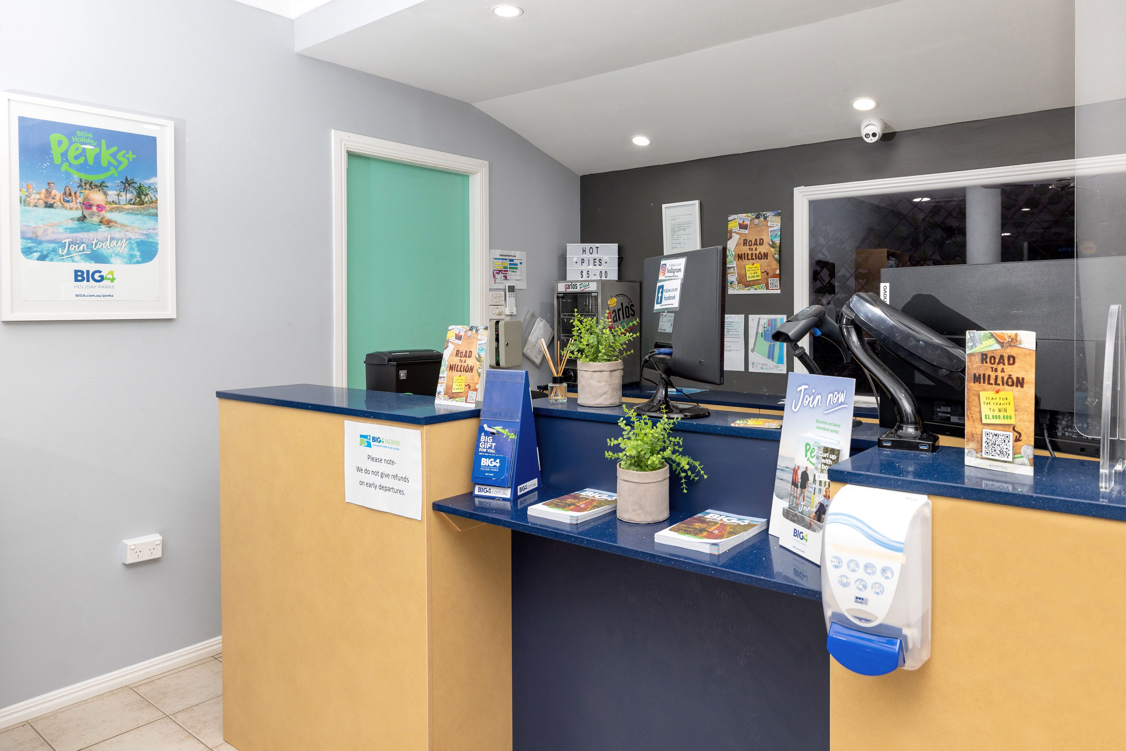 A reception desk with a blue counter, a green door, and various informational posters.