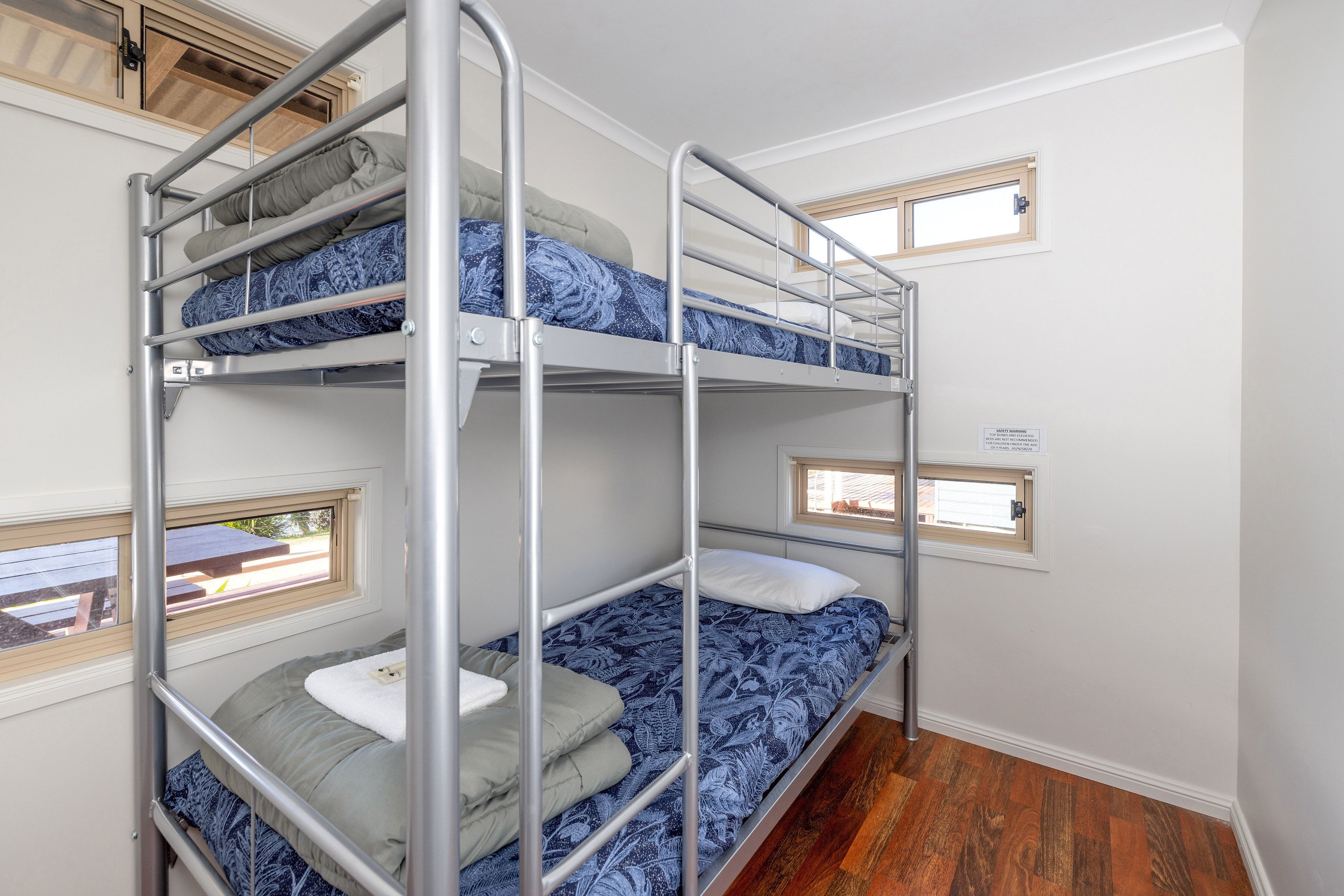 A bunk bed room with three levels, each with a window.