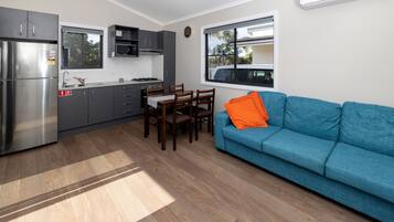 Ett kompakt bostadsutrymme med ett litet kök, en matplats och en soffa.
