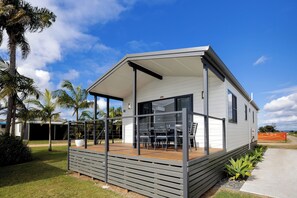 Una casa móvil moderna con un porche cubierto, comedor y garaje.