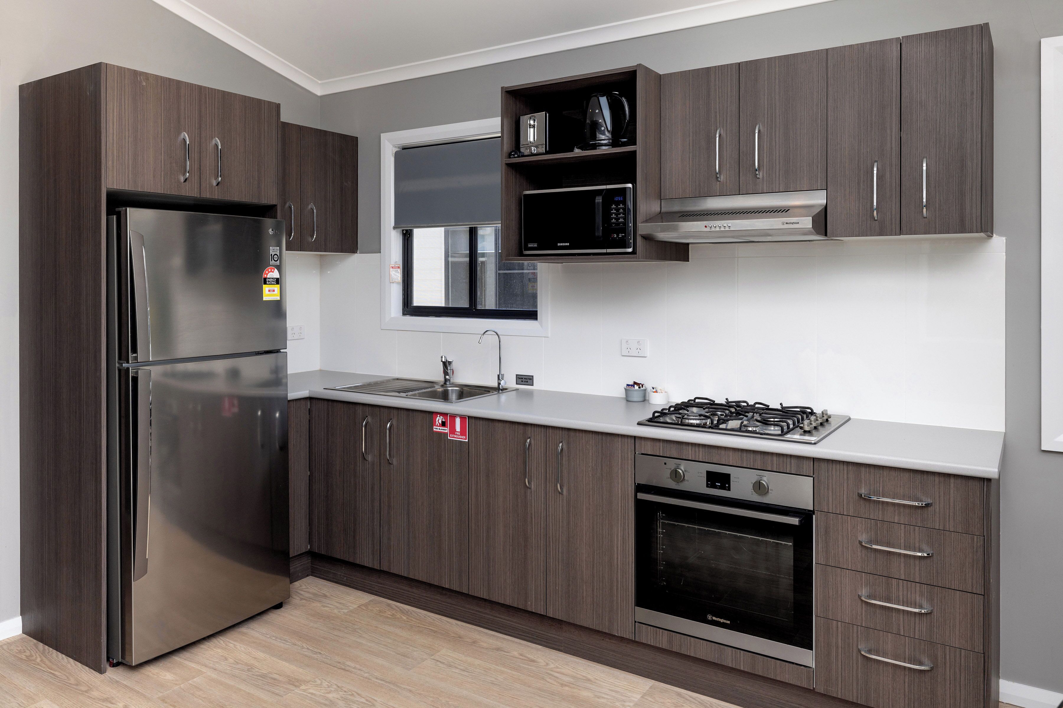 A modern kitchen with a stainless steel refrigerator, microwave, gas stove, and oven.