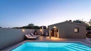 Une piscine sur le toit, dotée de chaises longues, et un petit bâtiment avec une porte et des fenêtres.