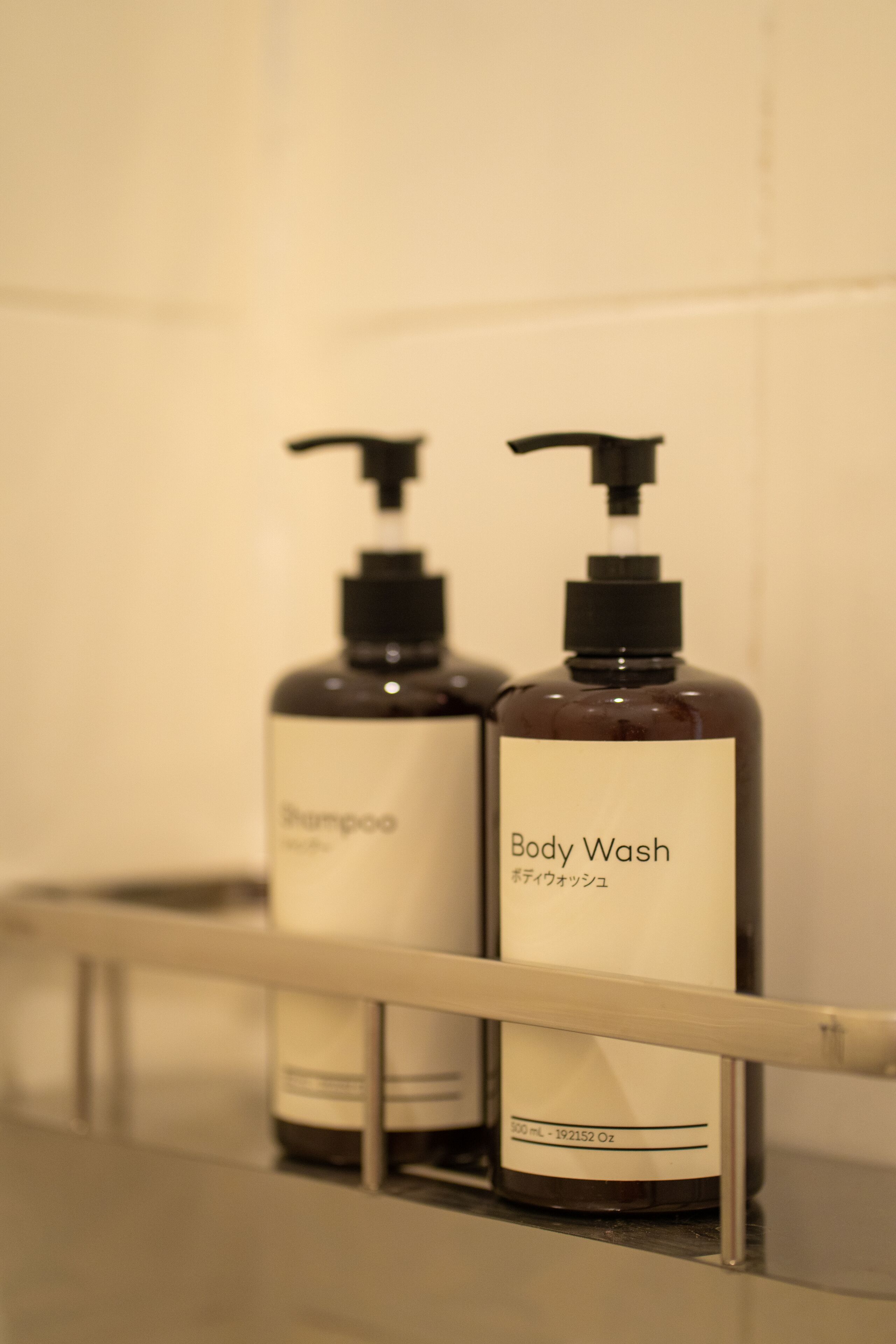 Two bottles of shampoo and body wash on a bathroom shelf.