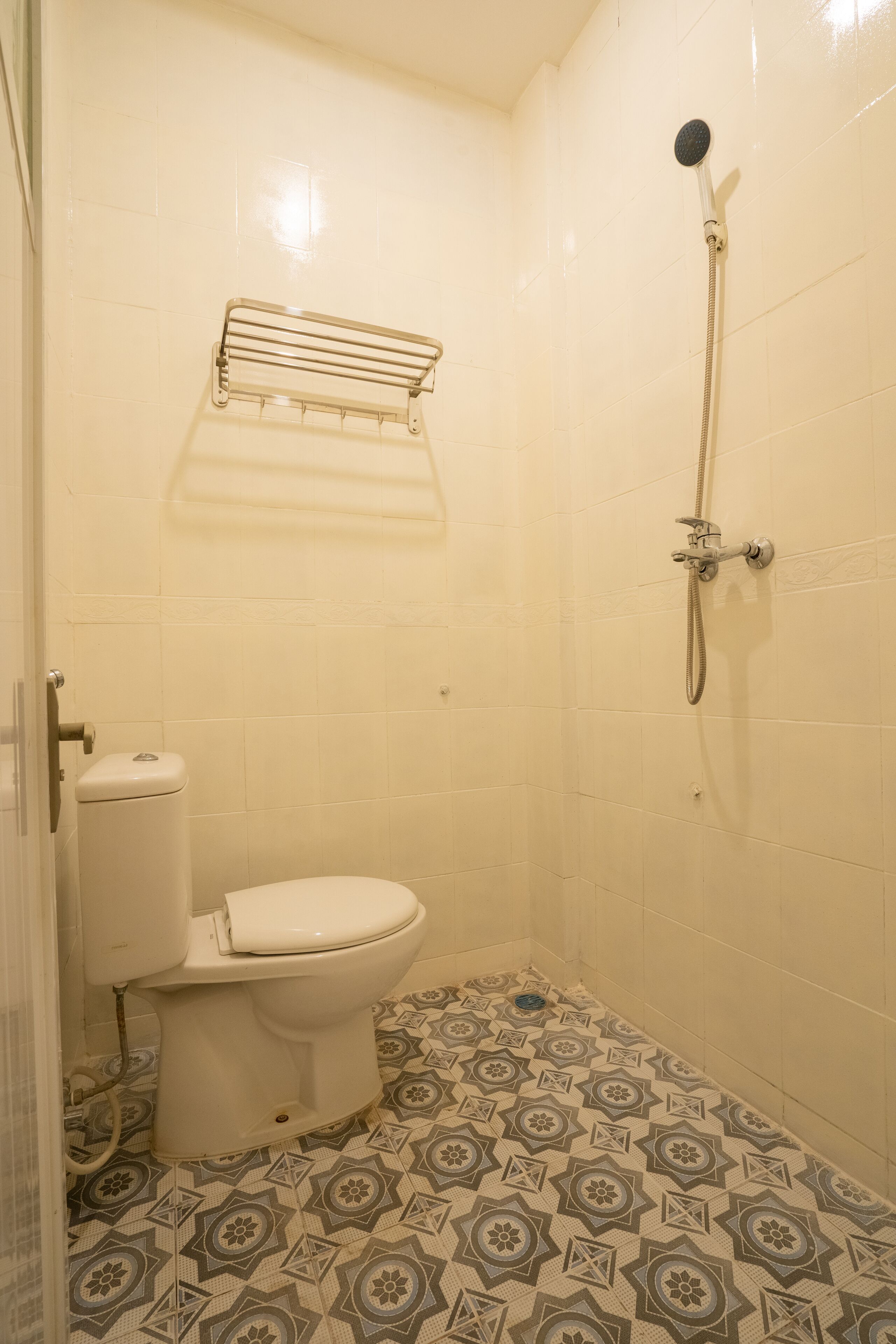 A small bathroom with a toilet, a shower, and patterned floor tiles.
