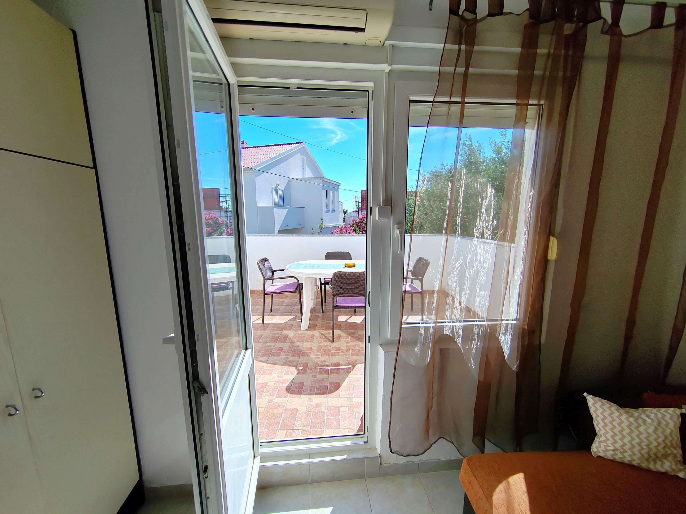 A room with a sliding glass door leading to an outdoor patio with a table and chairs.