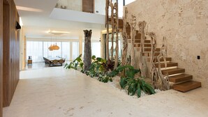 Un intérieur spacieux avec un plafond haut, un escalier en bois et un coin repas comprenant une grande table et des chaises.