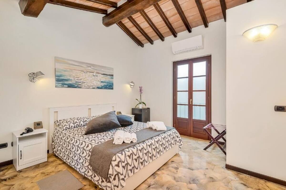 Une chambre à coucher avec une couvre-lit à motifs, une table de chevet, une lampe fixée au mur, un tableau et une porte en bois.