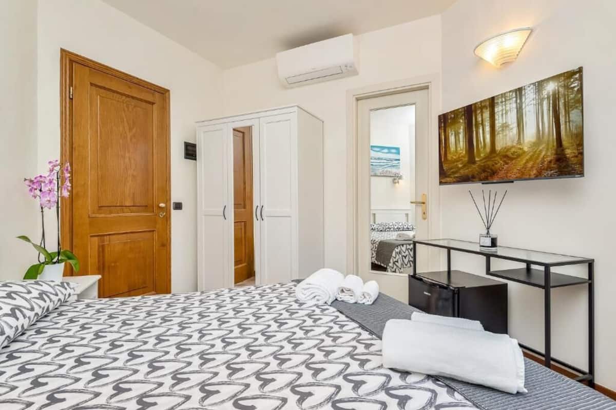 Une chambre d’hôtel avec un grand lit, un bureau, un miroir et un tableau au mur.