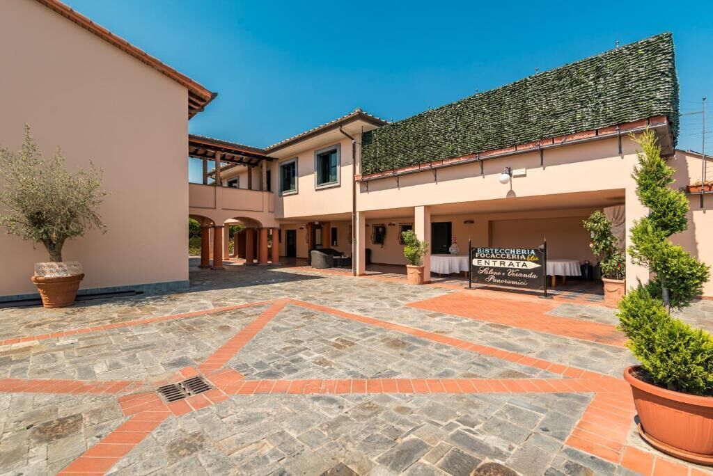 Ein Innenhof mit Steinpflaster, ein Gebäude mit Ziegeldach und ein Schild für ein Restaurant.