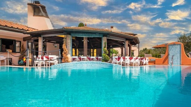 A swimming pool with lounge chairs and a covered area. - Hotel la Pietra Restaurant (Fosdinovo)