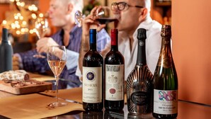 A table with various bottles of wine and a glass of white wine, along with some food items. - Hotel la Pietra Restaurant (Fosdinovo)