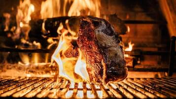 Un gran trozo de carne asándose sobre fuego vivo.