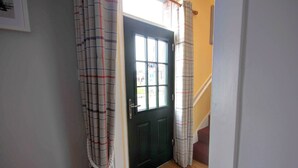 A hallway with a black door, a staircase, and a window. - Red Brick Former Railway Workers' Cottage (Brora)