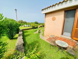 A house with a stone pathway leading to a tiled patio with a metal table and chairs. - Villetta Miriacheddu (San Teodoro)