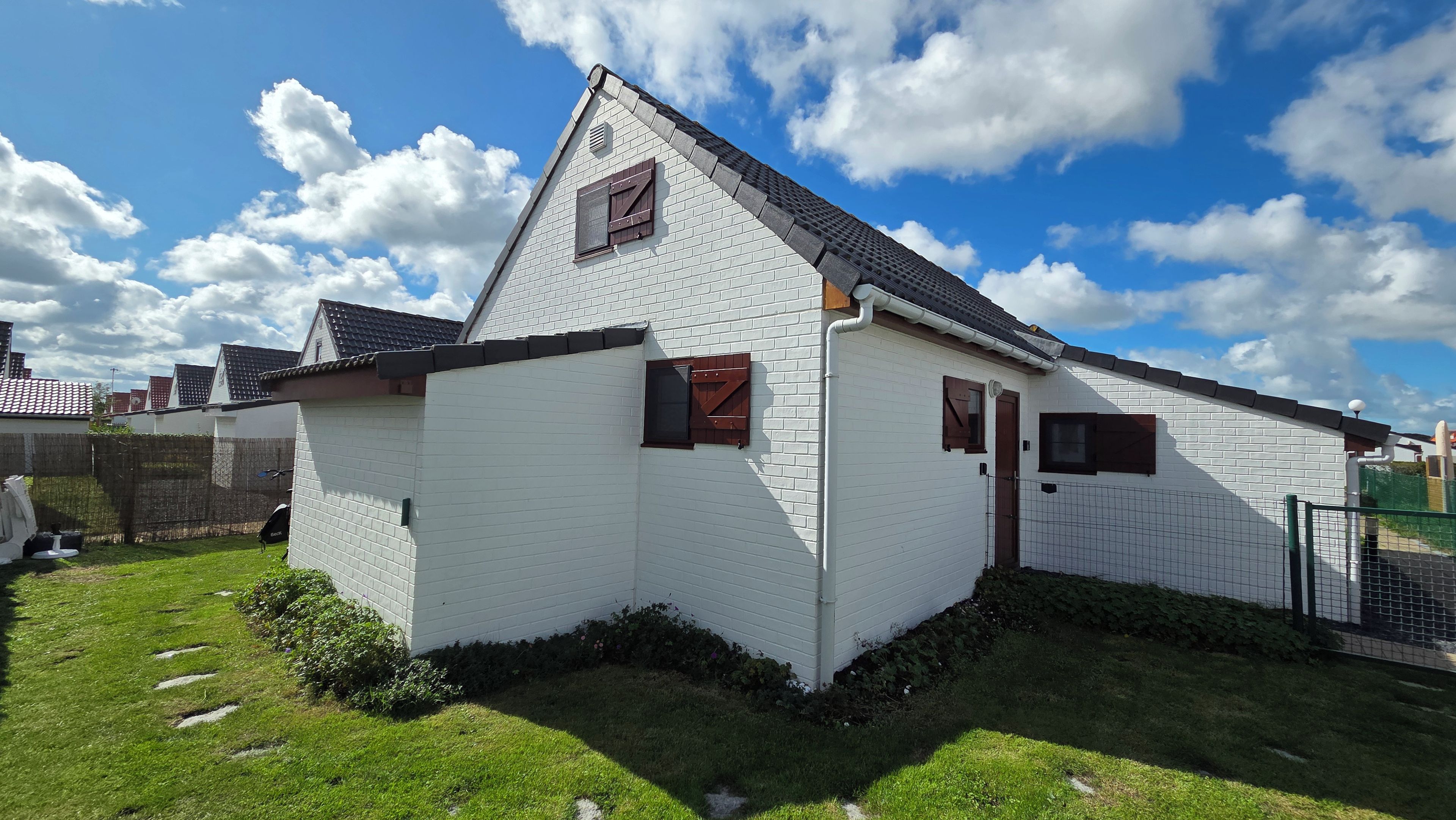 A white building with a sloped roof, a small window, and a door.