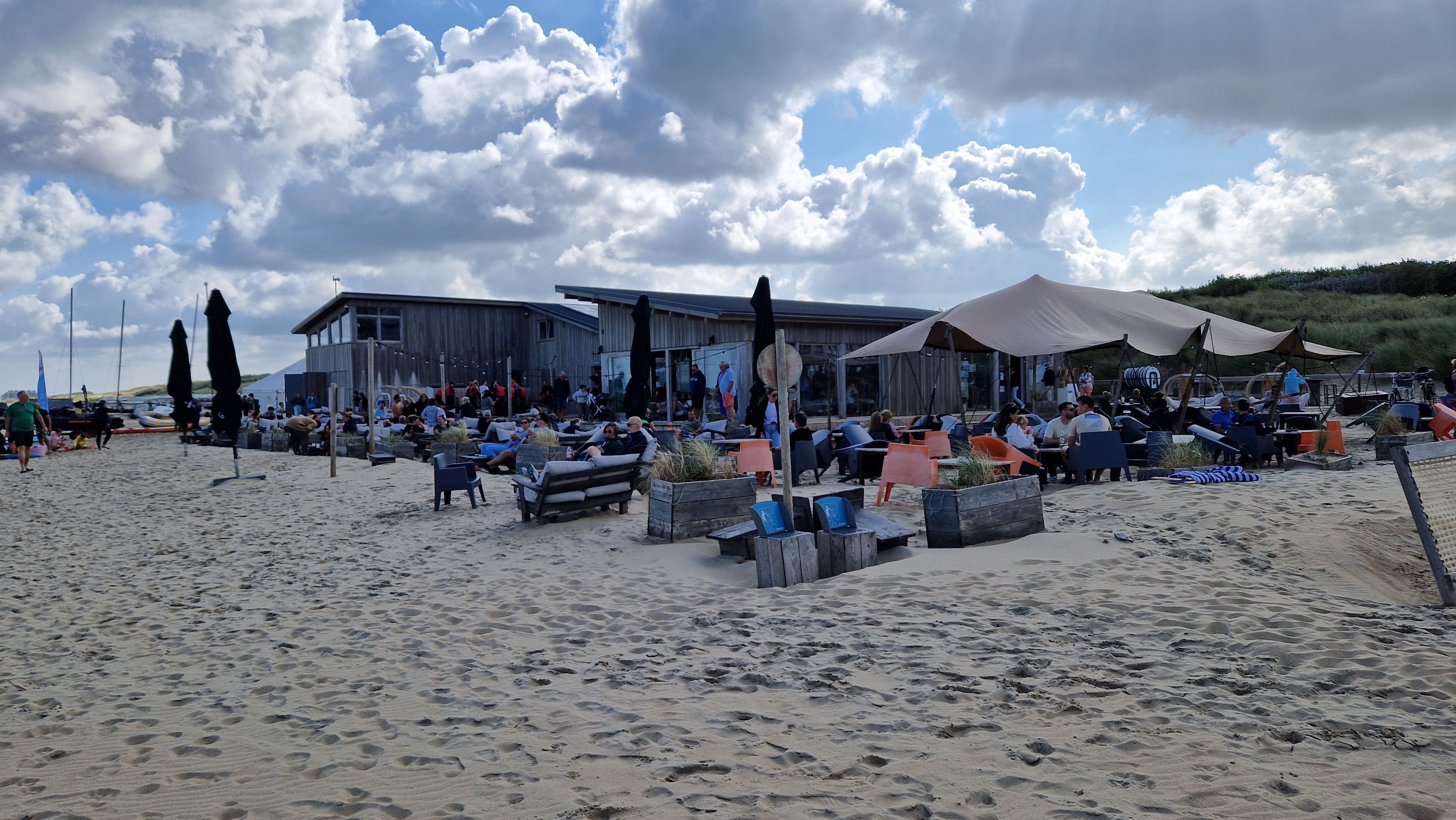 A beachside restaurant with outdoor seating and a building in the background.