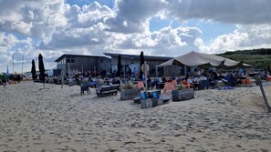 A beachside restaurant with outdoor seating and a building in the background. - Fisherman's cottage in Wenduine, close to the beach and marina of Blankenberge.  (De Haan)