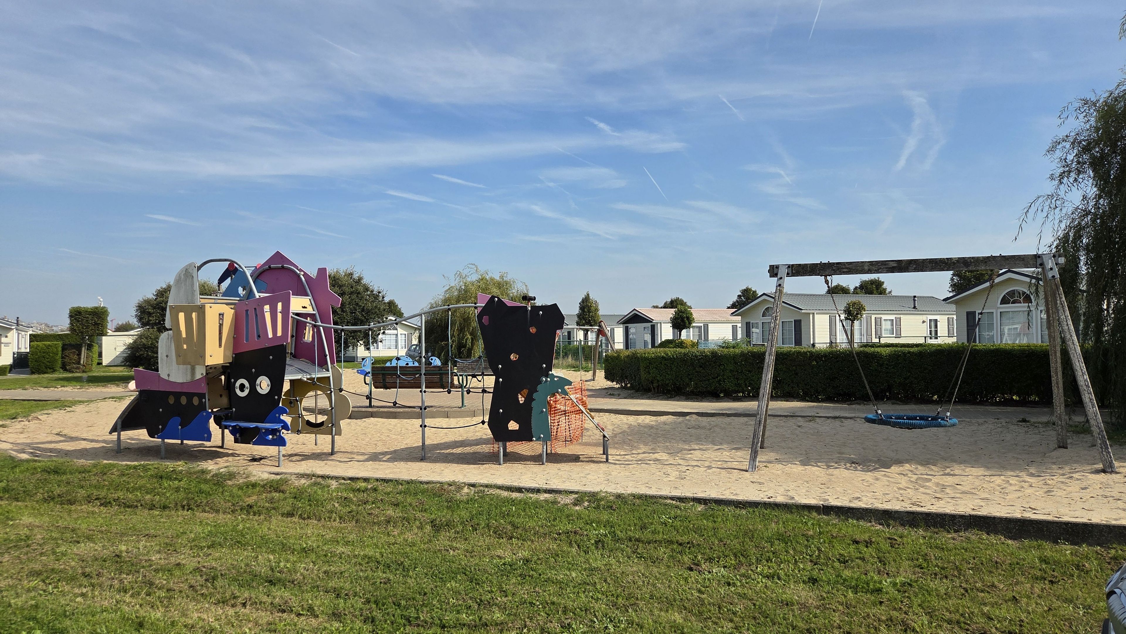A playground with climbing structures and a swing set in a residential area.