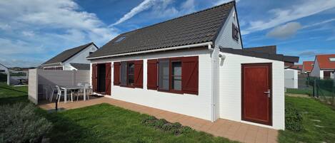 A residential building with a tiled roof, a fenced backyard, and a patio with outdoor furniture.