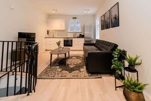 A modern living room with a sofa, coffee table, and potted plants.