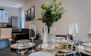 Mesa de comedor lista con cristalería transparente y un centro de decoración con plantas.