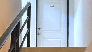 Eine Treppe führt zu einer Tür, die mit der Nummer 102 gekennzeichnet ist.