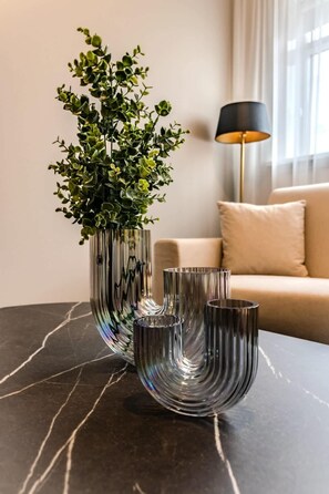 A modern living room with a marble table, a tall vase with green foliage, and a floor lamp. - Framnesvegur - Two Bedroom Central Apartment (Reykjavík)