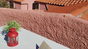 A table with a book and a red lantern, overlooking a coastal area with terracotta-roofed buildings and a clear blue sky. - Arianna House (Borgo Rocce Rosse Arbatax) (Arbatax)
