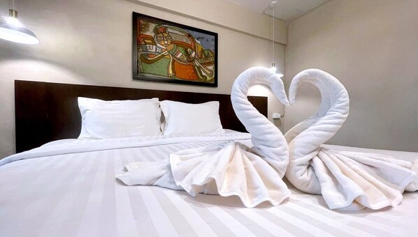 A hotel room with a bed, pillows, and a painting on the wall.