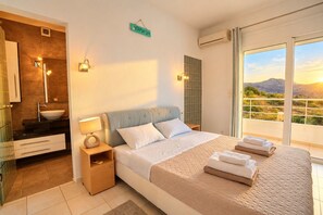 A hotel room with a bed, a bathroom, and a balcony with a view.