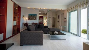 Un saló modern amb un sofà modular, una taula de centre de vidre i una zona de menjador amb cadires.