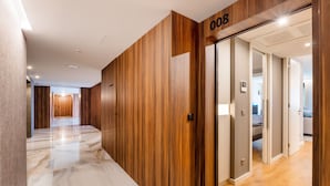 En modern hotellkorridor med träpanel på väggarna, ett marmorgolv och en dörr som är märkt med numret 008.