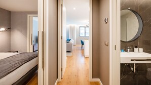 Ett modernt hotellrum med en säng, ett skrivbord och ett badrum med en stor spegel.