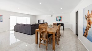 A spacious living area with a dining table, chairs, a sofa, and a large painting of a giraffe. - Heinlen on North Terrace  (Mount gambier)