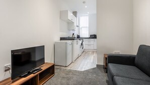 Una sala de estar moderna con un televisor de pantalla plana, un sofá gris y una pequeña mesita de madera.
