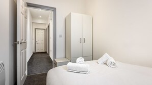 Una habitación de hotel con cama, un armario y un pasillo que da a otra habitación.