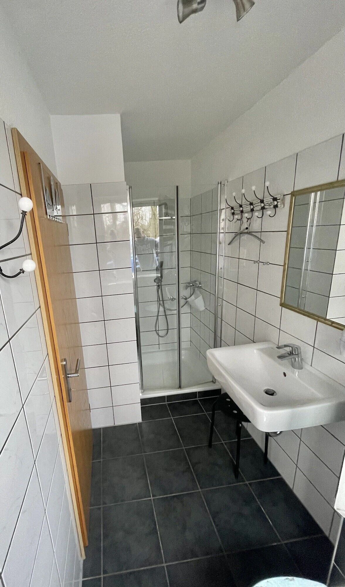 A modern bathroom with a glass shower enclosure, a white sink, and tiled walls.