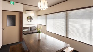 A modern meeting room with a wooden table, a vase with flowers, a bench, and a large window with blinds. - Hakone no Yado (Hakone)