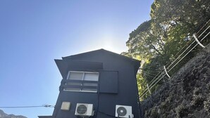 A black building with two air conditioning units, a door, and a small window. - Hakone no Yado (Hakone)