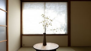 A tatami room with a round table and a vase with branches. - Hakone no Yado (Hakone)
